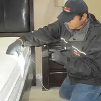 Bed bug inspection technician checking a mattress and bed frame for signs of infestation in Aurora, IL