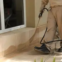 General pest control technician spraying exterior perimeter around a home in Aurora, IL