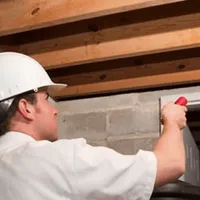 Termite inspection technician checking a basement wall and framing for termite activity in Aurora, IL