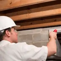Termite inspection technician checking a basement wall and framing for termite activity in Aurora, IL